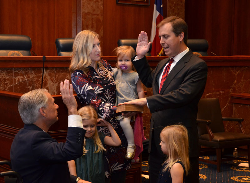 His left hand on the Bible, his wife, Jessica, and daughters beside him, Justice Blacklock repeats his office oath as Gov. Abbott administers it.